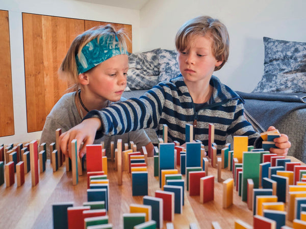 Ein achtjähriger Junge spielt sehr konzentriert mit seinem sechsjährigen Bruder mit PESTAs Dominosteinen